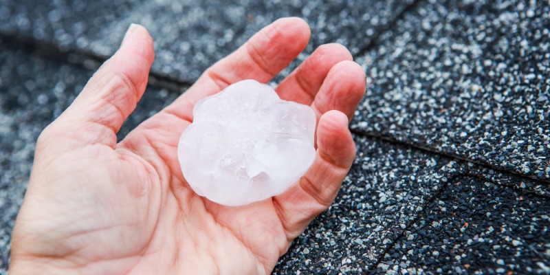 Homeowner holds hail near a roof.